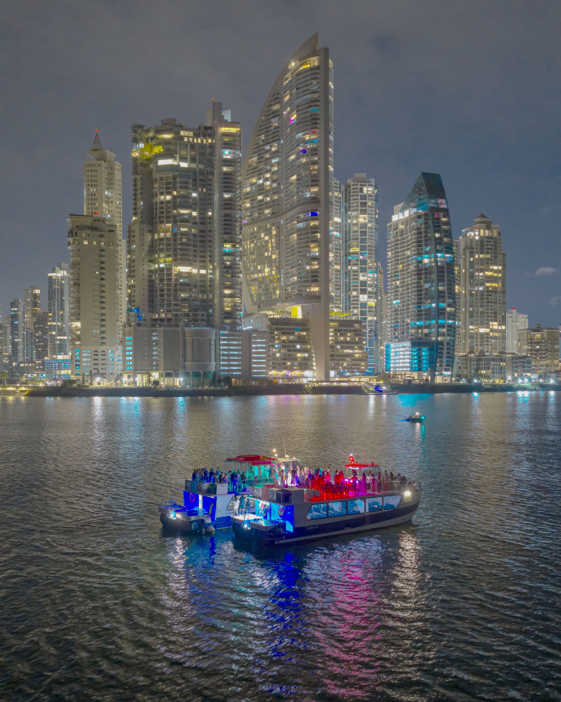 El catamarán iluminado de fiesta de noche con el skyline encendido